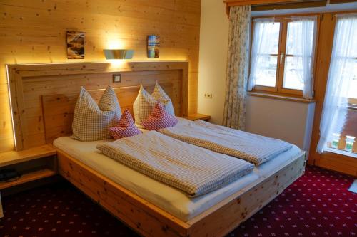 Schlafzimmer mit einem großen Bett mit einem Kopfteil aus Holz in der Unterkunft Ferienwohnung Rennerlehen in Schönau am Königssee