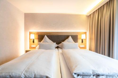 two beds in a hotel room with white pillows at Hotel Restaurant Waldsägmühle in Pfalzgrafenweiler