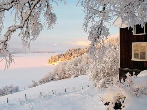 una casa cubierta de nieve junto a un campo cubierto de nieve en 5 person holiday home in Lomen, en Løken