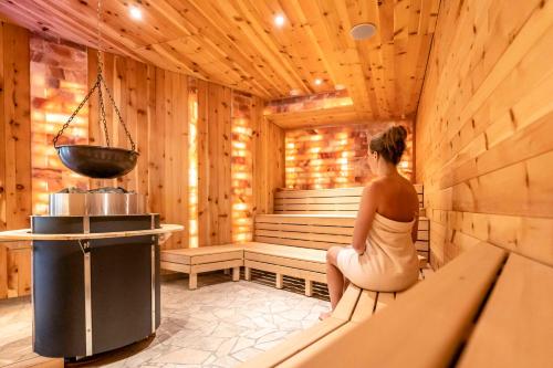 a woman is sitting in a sauna at Hotel Restaurant Waldsägmühle in Pfalzgrafenweiler