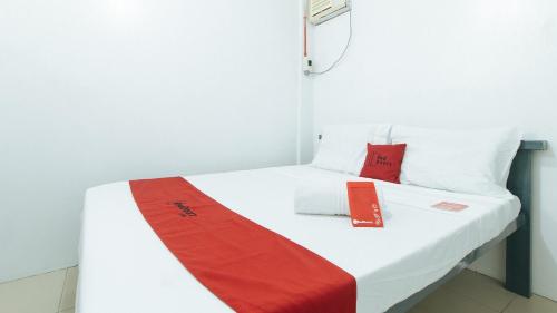 un letto in una camera con coperta rossa e bianca di RedDoorz @ Shukran Rentals OPC Pampanga a Candaba