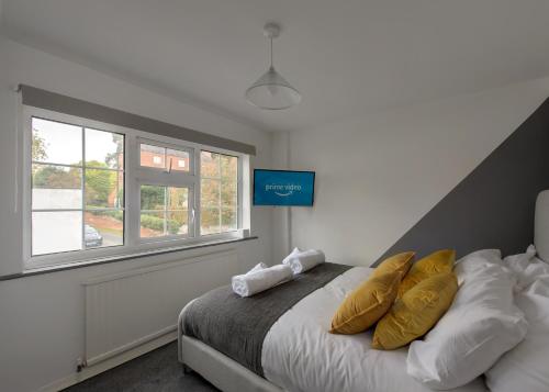 Un dormitorio con una cama con almohadas amarillas y una ventana en Donington Cottage Apt 6 en Castle Donington
