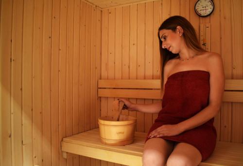 a woman sitting in a sauna holding a bucket at ADAM Hotel Suites in Tunis