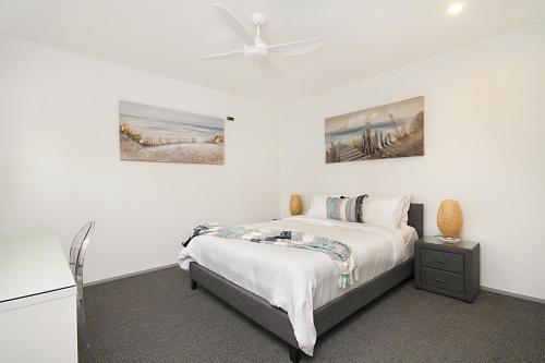 a white bedroom with a bed and a ceiling fan at Spacious 3 bedroom apartment opposite surf club in Kingscliff