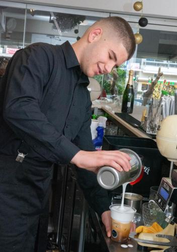 a man standing in a kitchen preparing a drink at Leto Boutique Hotel Agrinio in Agrinion