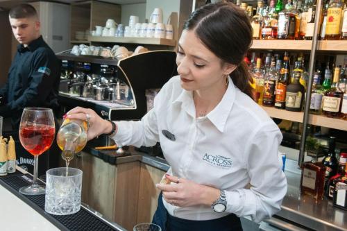 a woman preparing a glass of wine at a bar at Leto Boutique Hotel Agrinio in Agrinion