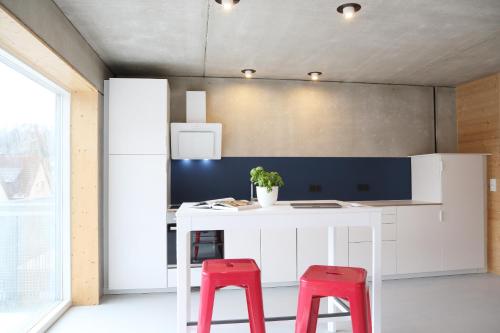 a kitchen with a white island with two red stools at Serviced Apartments - FeWo im Herzen Königsbronns in Königsbronn