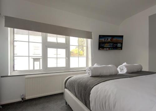 a white bedroom with a bed and two windows at Donington Cottage Apt 5 in Castle Donington