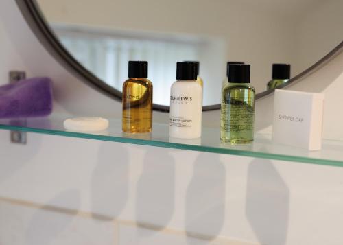 a shelf with four bottles of essential oils in front of a mirror at Donington Cottage Apt 5 in Castle Donington