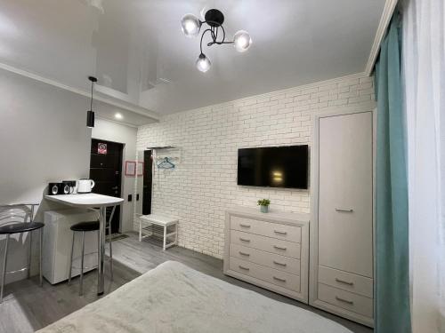 salon z telewizorem na białej ceglanej ścianie w obiekcie Tiffany Apartment w mieście Irpień