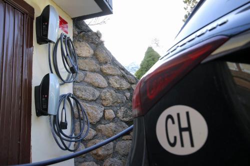 a car parked next to a stone wall with a charger at Hotel Schweizerhof Sta Maria in Sta Maria Val Müstair