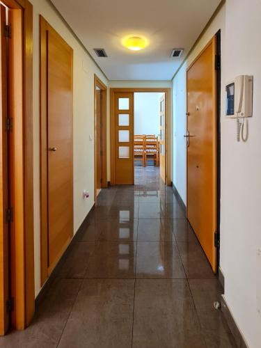 a hallway with wooden doors and tile floors at Apartamento Completo Torresol V in Benidorm