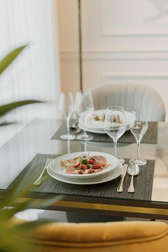 a table with two plates of food and wine glasses at Hotel Divine Park in Svilajnac