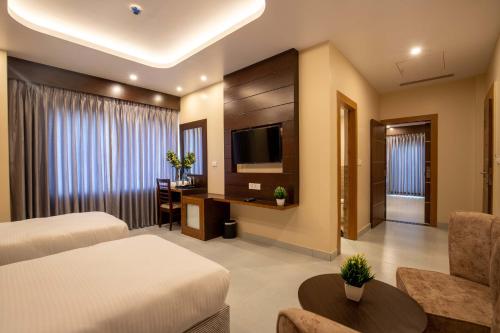 Habitación de hotel con 2 camas y TV de pantalla plana. en Hotel Palm International, en Butwāl