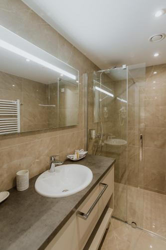a bathroom with a sink and a glass shower at Hotel Divine Park in Svilajnac
