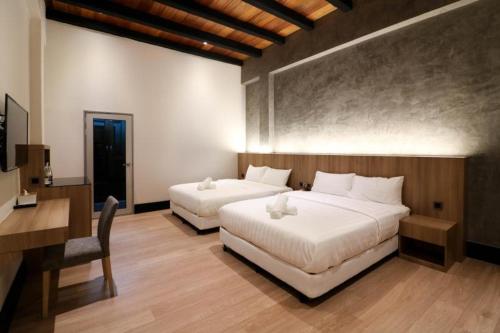 a bedroom with two beds and a desk and a desk at The NINES HOTEL Malacca in Melaka