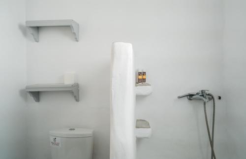 a white bathroom with a toilet and shelves on the wall at Cape Napos in Faros