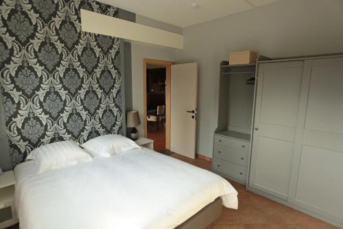 ein Schlafzimmer mit einem weißen Bett und einer Wand in der Unterkunft Le Moulin de Nancy in Hour
