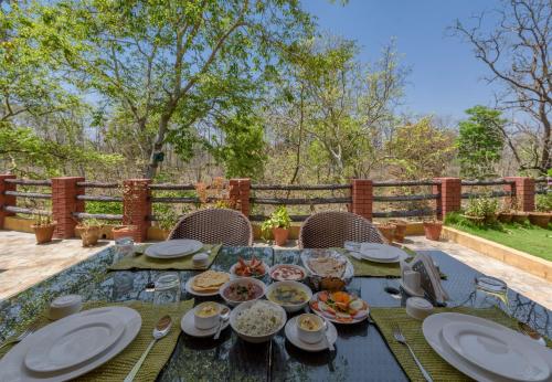a table with plates and bowls of food on it at The Riverwood Forest Retreat Pench in Khawāsa