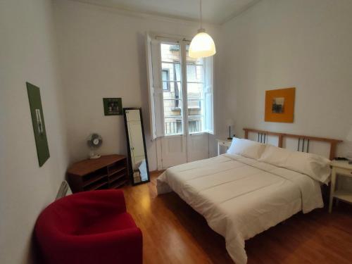 a bedroom with a bed and a red chair at Esparteria 1 in Barcelona