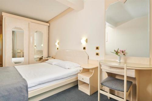 a bedroom with a bed and a desk with a chair at Hotel Gran Vista Plava Laguna in Poreč