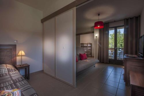 1 dormitorio con 1 cama y 1 sofá en una habitación en Vacancéole - Résidence Le Clos du Rocher en Les Eyzies-de-Tayac