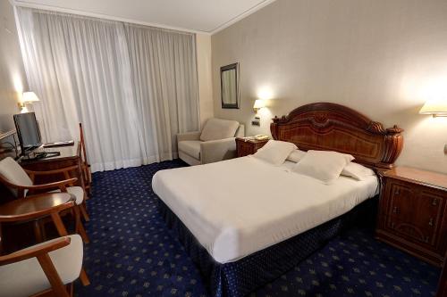 Cette chambre comprend un grand lit et une chaise. dans l'établissement Hotel Vila-real Palace, à Villareal