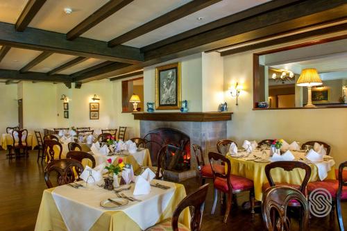 a restaurant with tables and chairs and a fireplace at Arusha Serena Hotel in Nkoanrua