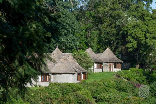 an old house with thatched roofs in a garden at Arusha Serena Hotel in Nkoanrua