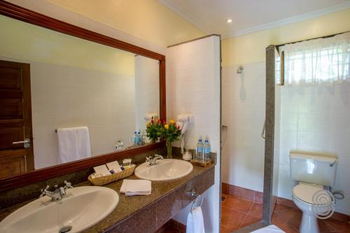 a bathroom with two sinks and a toilet and a mirror at Arusha Serena Hotel in Nkoanrua