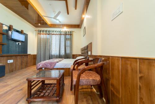 ShamshiMathan View Homestay - 3min Drive to Kullu-Manali Airport的一间有床、桌子和电视的房间