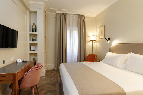 a hotel room with a bed and a desk and a television at Hotel Smeraldo in Rome
