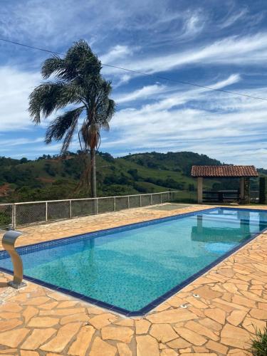a swimming pool with a palm tree in the background at Fazenda Mantiqueira e Restaurante in Camanducaia
