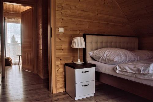a bedroom with a bed and a lamp on a night stand at Wioska Jasia i Małgosi in Izdebnik