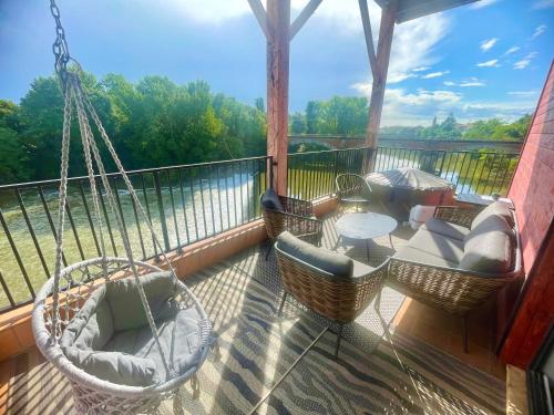 eine Veranda mit einer Hängematte, Stühlen und einem Tisch in der Unterkunft Suite prestige « Paradis » 5* au Moulin d’Albias in Albias