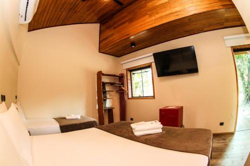 um quarto com 2 camas e uma televisão de ecrã plano em Bossa Beach House na Ilha do Mel