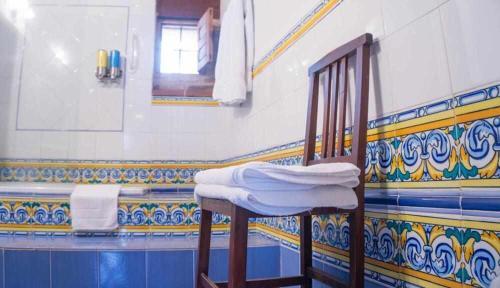 アレーナス・デ・サン・ペドロにあるPosada El Canchalの青と黄色のタイル張りの壁のバスルーム(椅子付)