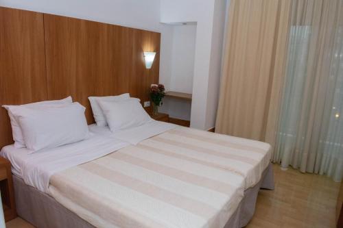 a bedroom with a large bed with white pillows at Leto Boutique Hotel Agrinio in Agrinion