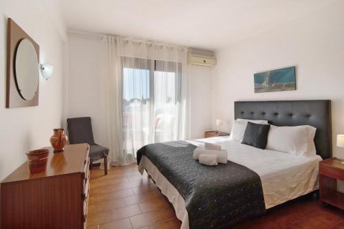 1 dormitorio con cama, escritorio y ventana en T2 Balaia, en Albufeira