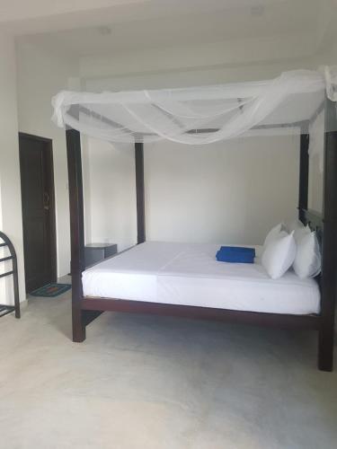 a bedroom with a white bed with a canopy at Waves Hiri Sea View in Hiriketiya