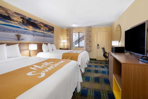 a hotel room with two beds and a flat screen tv at Days Inn by Wyndham Alamogordo White Sands in Alamogordo