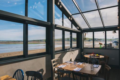 een restaurant met tafels en ramen met uitzicht op het strand bij The Royal George in Appledore