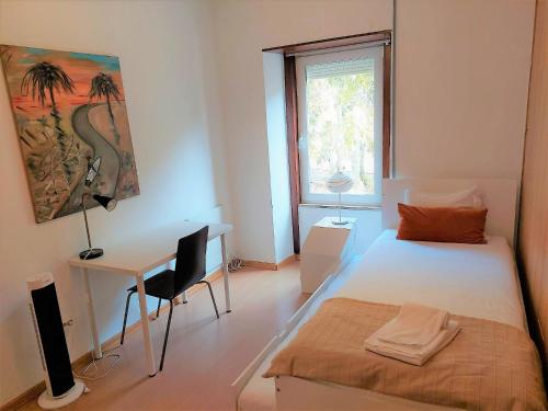 1 dormitorio con cama, escritorio y ventana en Sweet Garden in Cascais - Checkinhome, en Cascais