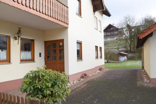 a white house with a wooden door and a yard at OB Ferienwohnung Sensbachtal in Untersensbach