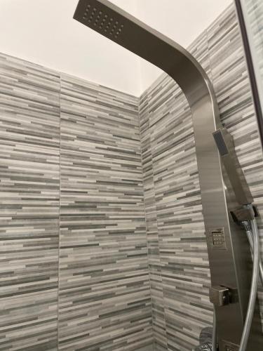 a bathroom with a shower with a tile wall at Rosa Dei Venti Apartment in Catania