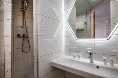 a white bathroom with a sink and a mirror at Hotel Marena in Paris