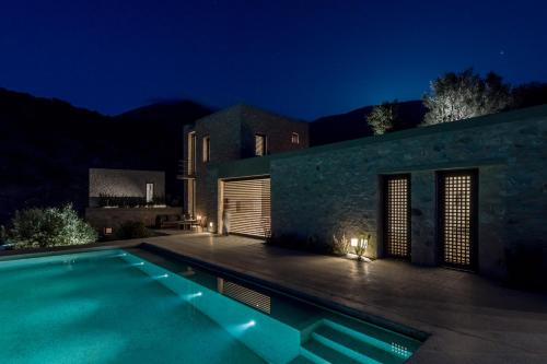 a house with a swimming pool at night at Monolithoi Villas in Piyí