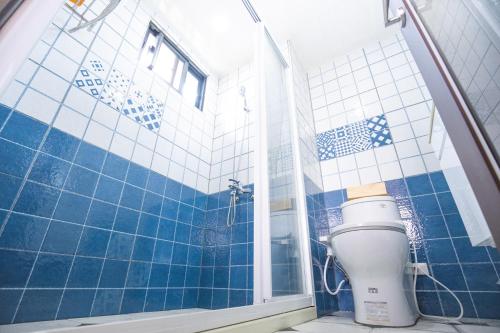 uma casa de banho em azulejos azuis com um WC e um chuveiro em 亞窩行館 Yao Guesthouse em Nangan