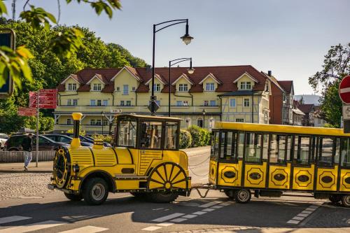 a yellow train car driving down a street at Boutiquehotel Schloßpalais in Wernigerode