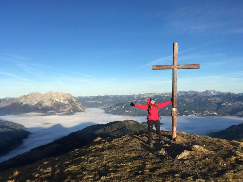 a person standing next to a wooden cross on a mountain at Sunlodge Oeblarn Top C3 Schladming-Dachstein in Öblarn
